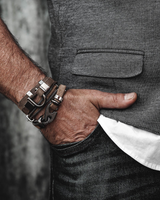 Person wearing a gray vest, white shirt, and dark jeans with a focus on their wrist and hand.