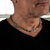 Minimalist stainless steel choker necklace on a model, featuring dark silver rectangular and oval links.