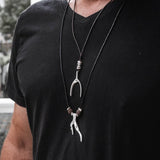Men's layered necklaces featuring a silver wishbone and coral pendants on an adjustable black cord.