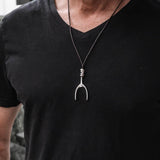 Men's adjustable black cord necklace featuring a metal wishbone pendant, worn over a black V-neck shirt.