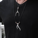 Two layered adjustable necklaces worn on a man's chest, featuring a silver wishbone and a coral pendant with brown lava stones.