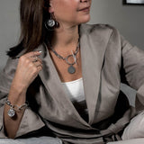 Contemporary statement earrings with Greek coin pendants, featuring brass elements and a sleek, edgy design.