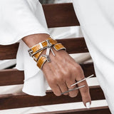 Striking yellow leather wrap bracelet with a bold buckle, paired with a matching silver bangle on a model's wrist.