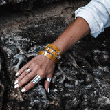 Yellow leather wrap bracelet stacked with a matching bangle, featuring bold buckles and silver metal accents.
