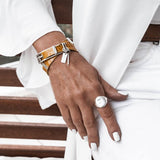 Striking yellow leather wrap bracelet with bold buckle paired with a silver antique plated brass bangle, worn on a wrist.
