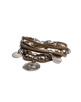 Boho-style bracelet featuring four beige suede strands, silver-plated cube beads, and charms resembling ancient Greek coins.