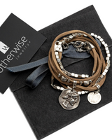 Suede boho bracelet featuring four strands, silver-plated cubes, and charms resembling ancient Greek coins.