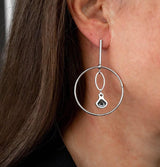 Elegant loop earrings in silver with a dangling Austrian crystal pendant, showcasing an edgy chic design.