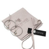 Elegant loop earrings in silver with a dangle Austrian crystal pendant placed on a suede pouch with branding.