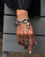 Chunky hammered metal link bracelet in antique silver worn on a woman's wrist, featuring a leather and wrought ball pendant.