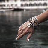 Silver-plated hammered metal bangle worn stacked with various bracelets on a model's wrist.