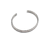 Silver-plated hammered bangle cuff with a minimal design, adjustable for stacking with other bracelets.