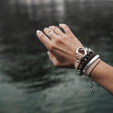 Silver metal bangle with a hammered texture, worn stacked with leather and beaded bracelets on a hand.