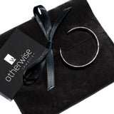 Hammered silver-plated metal bangle rests on a black suede pouch, featuring a sleek, minimal design ideal for stacking.