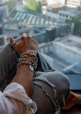 Unique hammered bangle worn stacked with other silver bracelets, showcasing a bold, edgy design against a casual outfit.