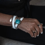 White leather wrap bracelet featuring a chunky turquoise resin stone, paired with a sleek metal cuff.