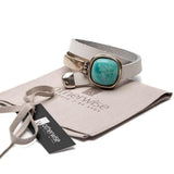 White leather wrap bracelet featuring a chunky turquoise resin stone and half metal cuff. Hinge closure for adjustability.
