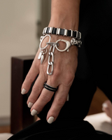Hand wearing multiple silver bracelets and rings with a blurred background