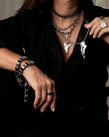 Person wearing multiple necklaces, bracelets, and rings with a blurred background