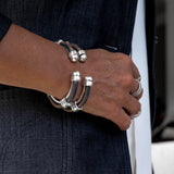 Silver-plated zamak cuff bangle with orange-stitched jeans cord and spring opening for layered everyday wear