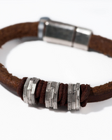 Brown leather bracelet with silver metal beads on a white background