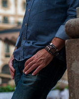 Person wearing a blue shirt and jeans standing in an outdoor setting with blurred background