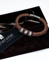 Brown leather bracelet with silver accents on a black jewelry box, branded 'otherwise jewelry'.