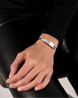 Irregular shaped silver-plated cuff bangle worn on a woman's wrist, paired with black leather pants.
