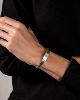 Silver-plated cuff bangle with an irregular shape, worn on a model's wrist, showcasing a minimal and classy design.