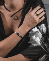 Irregular silver-plated cuff bangle worn on a woman's wrist, paired with a sleek black top and matching jewelry.