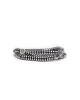 A silver-toned beaded stretch bracelet with a textured, segmented design and a small round charm featuring an 'S' logo, displayed on a clean white background.