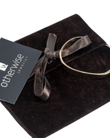 Rose gold cuff bangle rests on a dark suede pouch, showcasing its elegant design and flexibility for a comfortable fit.