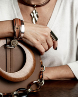 Rose gold cuff bangle worn on the wrist, featuring a flexible design for adjustable fit, paired with a leather bracelet.