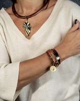 Rose gold cuff bangle worn stacked with other bracelets, featuring a flexible design for adjustable fit.