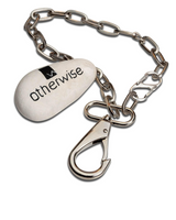 A silver metal chain accessory with a lobster clasp and a white teardrop-shaped tag printed with the black 'otherwise' logo, shown on a plain white background.