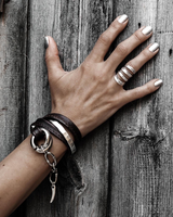 Chunky hammered silver-plated metal ring on a hand resting against rustic wooden panels, showcasing polished nails.