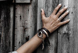 Chunky hammered silver-plated metal ring on a hand resting against rustic wooden panels, showcasing polished nails.