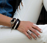 Chunky silver-plated hammered ring worn on a hand with metallic silver nails, alongside leather bracelets.