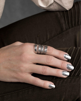 Chunky hammered silver-plated metal ring worn on a hand, showcasing a chic and edgy design.