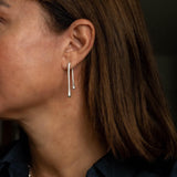 Minimal chic silver drop earrings with an irregular shape, hanging elegantly from the model's ear.