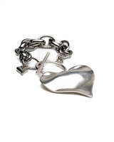 Chunky silver heart bracelet featuring a textured chain and a small heart charm, demonstrating an edgy design.