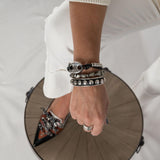 Antique silver bangle featuring black leather and silver stud chain, worn stacked with other bracelets.