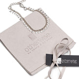Dainty 999 silver antique plated anklet with round charms, resting on a soft suede pouch with logo.
