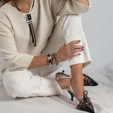 Antique silver bangle featuring black leather and a stud chain, stacked with other bracelets on a model's wrist.