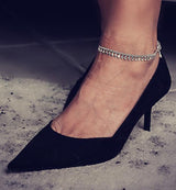 Dainty 999 silver antique plated anklet with charms, worn on an ankle next to a black high-heeled shoe.