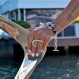 Adjustable two-finger ring in irregular geometric shape, shown in silver, worn on model's hand against a shiny surface.