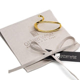 Adjustable gold two-finger ring with fluid, irregular design, displayed on a soft suede pouch.