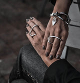 Adjustable two-finger ring in shiny silver, featuring irregular geometric shapes, worn on slender fingers with stylish nail polish.