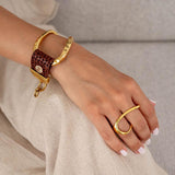 Adjustable two-finger ring in gold, showcasing a fluid, geometric design with graceful curves, worn alongside a gold and brown bracelet.