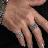 Close-up of a hand wearing two silver rings on a dark background